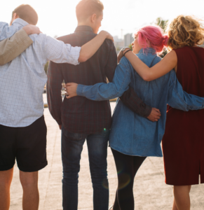 young people link arms and face away from the camera