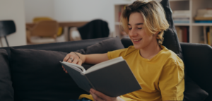young person reads a book on a couch