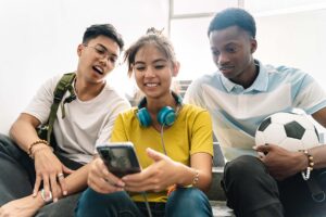 three teens smile and look at a phone while sitting in a stairwell looking up OCD help