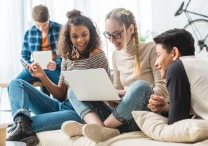 a group of young people look at a computer and smile as they contact Inward Healthcare