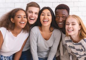 a group of young adults smiles at the camera against a brick wall after they contact Inward Healthcare