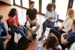 a group of people sit in chairs during a Cognitive Behavioral Therapy Program