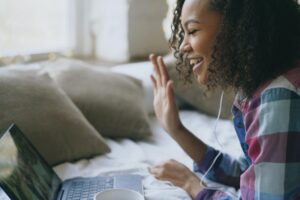 a young person waves and smiles at a video chat to represent a virtual intensive outpatient program