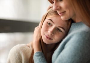 a teen leans against a parent in a hug during help with personality disorder treatment