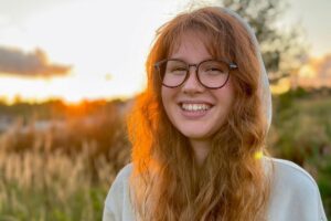 a young person smiles at the camera outside at sunset after getting depression help